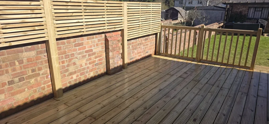 Grooved timber decking with a handrail and spindles across the end of the deck