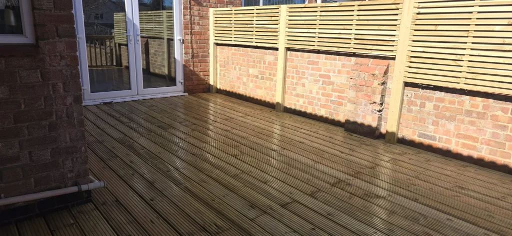 Slatted privacy screens fixed above the brick garden wall beside the deck