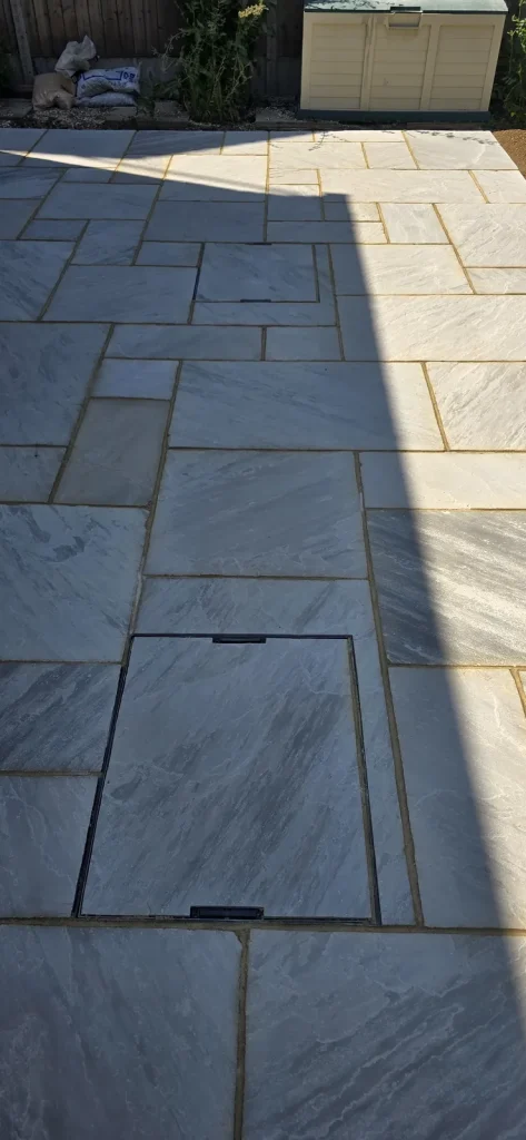 Recessed inspection cover filled with matching sandstone so it sits flush with the patio