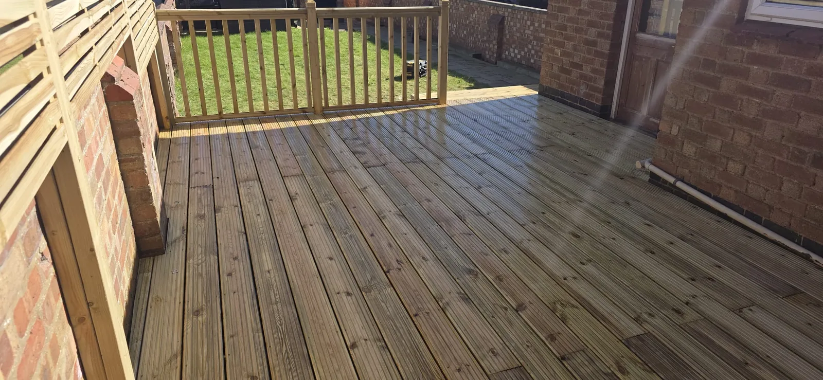 Timber decking with slatted privacy screens and a spindle balustrade in Abington, Northampton